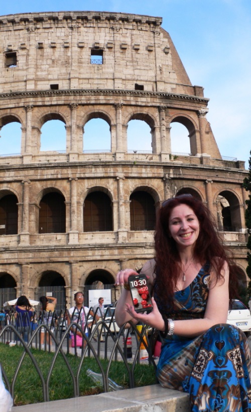 A woman posing in front of the Colosseum, Italy, while holding the LG Optimus G Pro.
