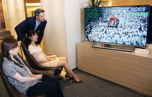 Travelers admiring the LG 55-inch OLED TV’s incredible display in an airport lounge.