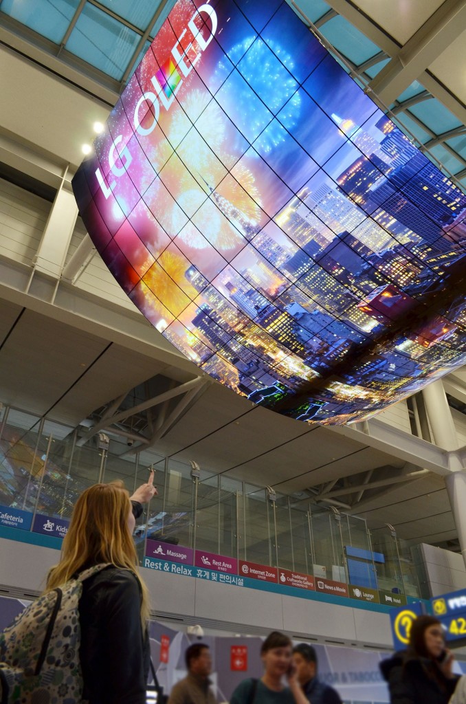 A ceiling installation of LG OLED Signage displaying a city’s skyline at night on display at Incheon International Airport.