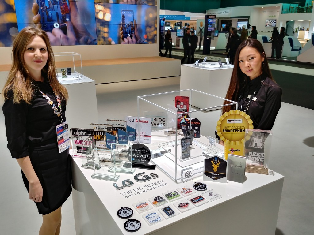 Two LG promoters standing behind two LG G6 devices and 31 booth awards that were given to the LG G6 at MWC 2017