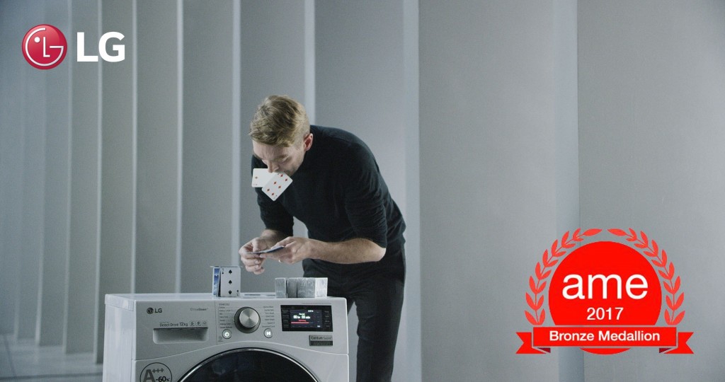 A professional card stacker Bryan Berg building house of card atop an LG Centum System™ washing machine with AME Award 2017 logo featured