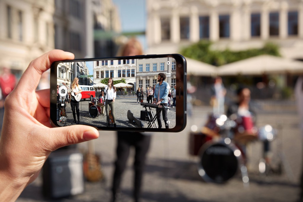 A person taking a picture with the LG Q6 of a band performing