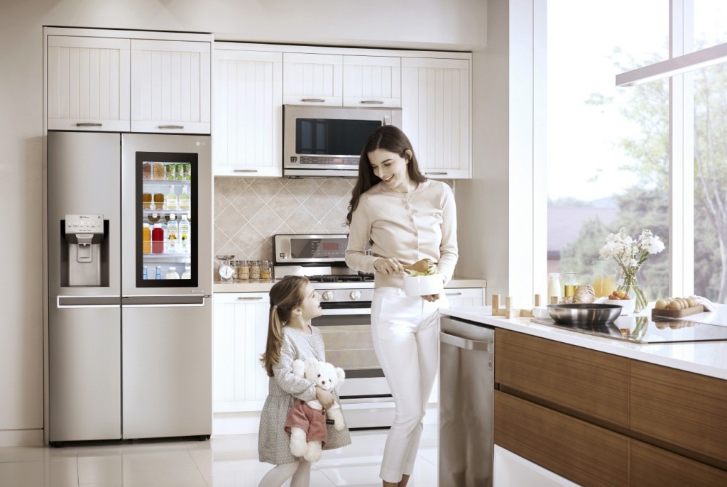 Woman and little girl holding a teddy bear standing in a kitchen with the LG InstaView Door-in-Door™ in the background