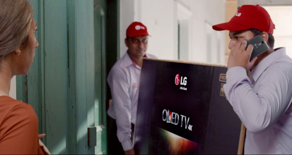 A screenshot of LG India’s “Astronaut” video, two men are delivering LG OLED TV to a woman’s house.