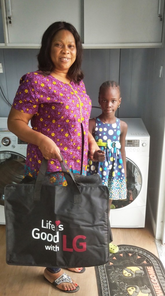 A woman stands with a little girl and smiles with LG’s gift bag in front of LG’s washing machine.