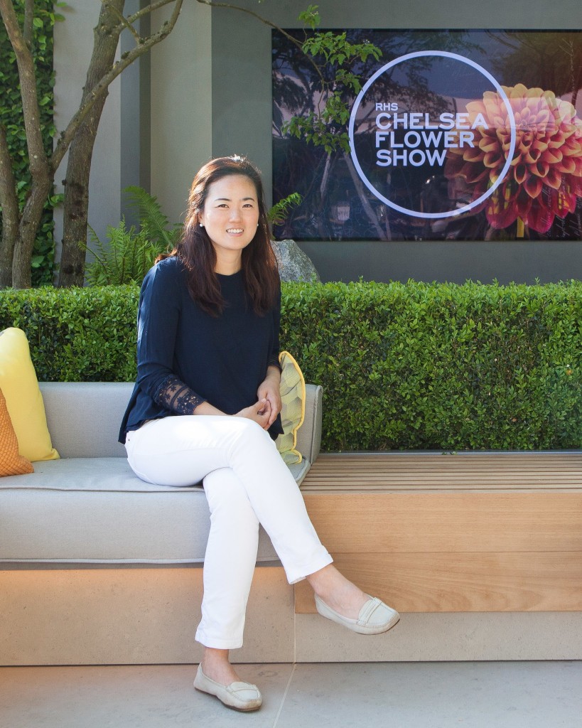 Korean landscape architect Hwang Hay-joung sits on a couch in front of the RHS Chelsea Flower Show logo.