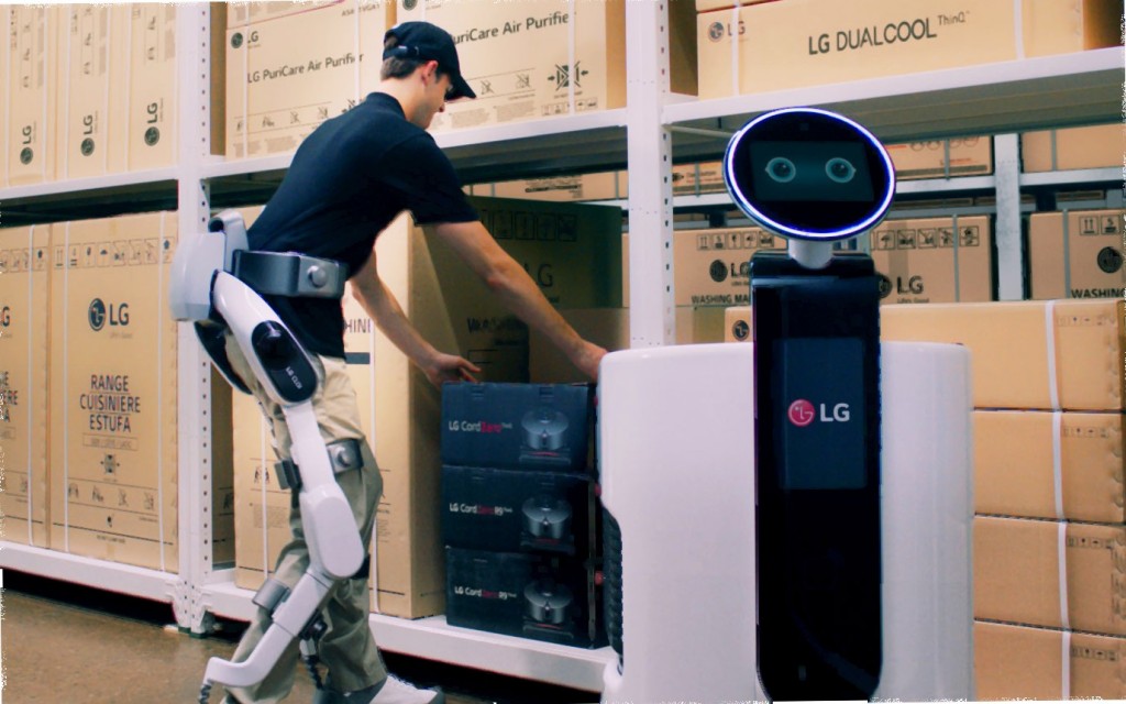 Man wearing LG CLOi SuitBot to move a box to the LG Shopping Cart Robot in a LG warehouse