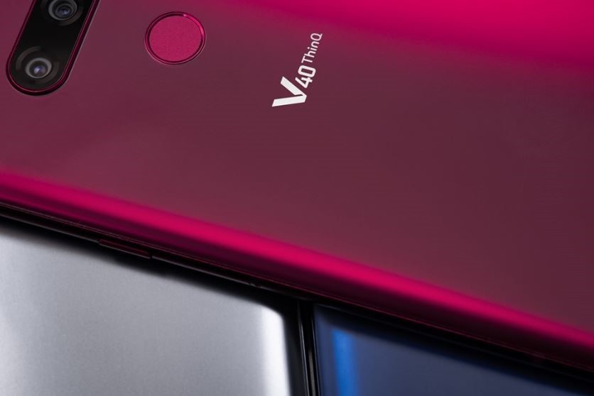 A Carmine Red LG V40 ThinQ is placed on LG V40 ThinQ smartphones in two different colors – New Platinum Grey and New Moroccan Blue.