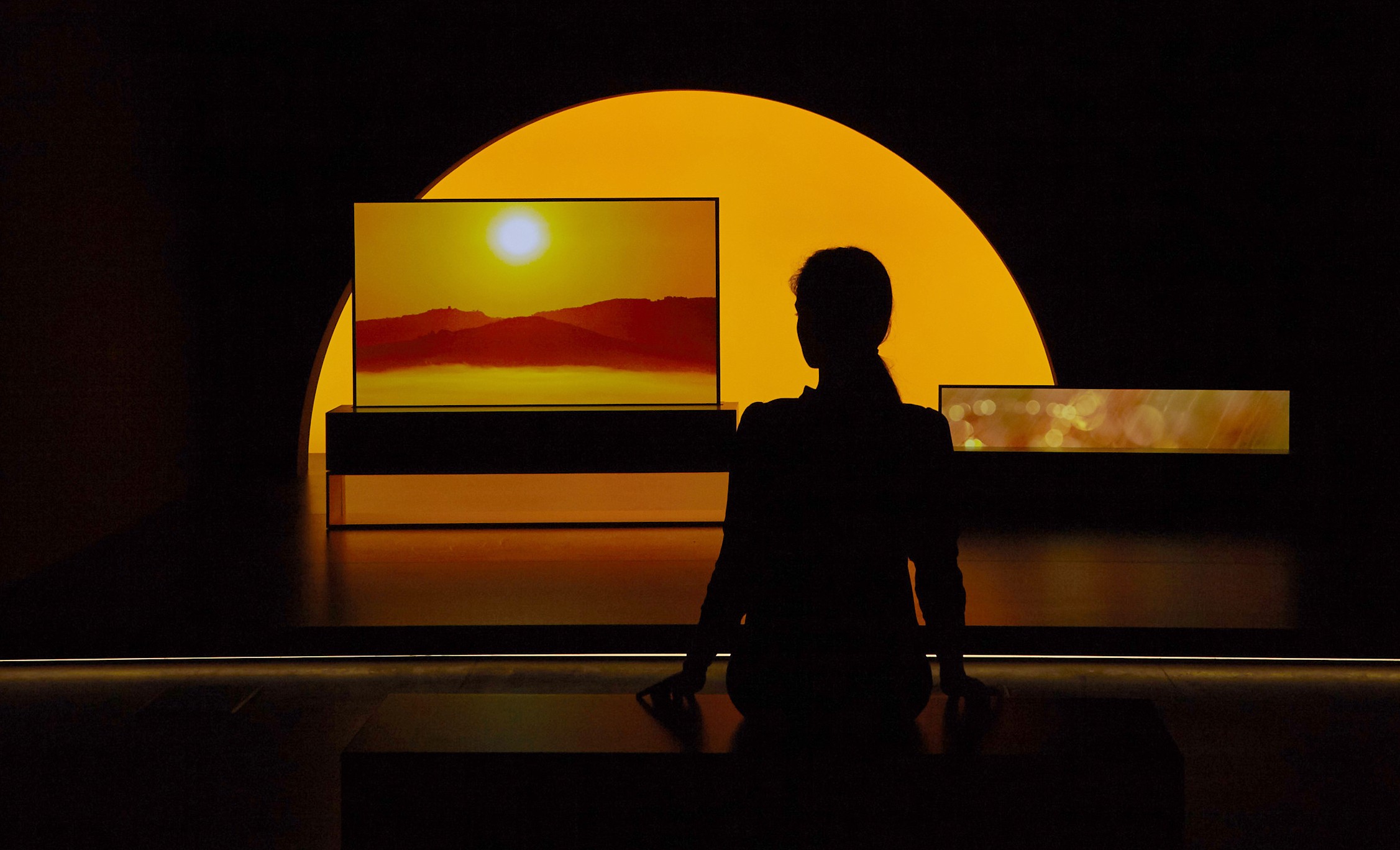 LG SIGNATURE OLED TV R model 65R9 displayed in the dark for the Redefining Space installation, with a model standing in front at Milan Design Week.