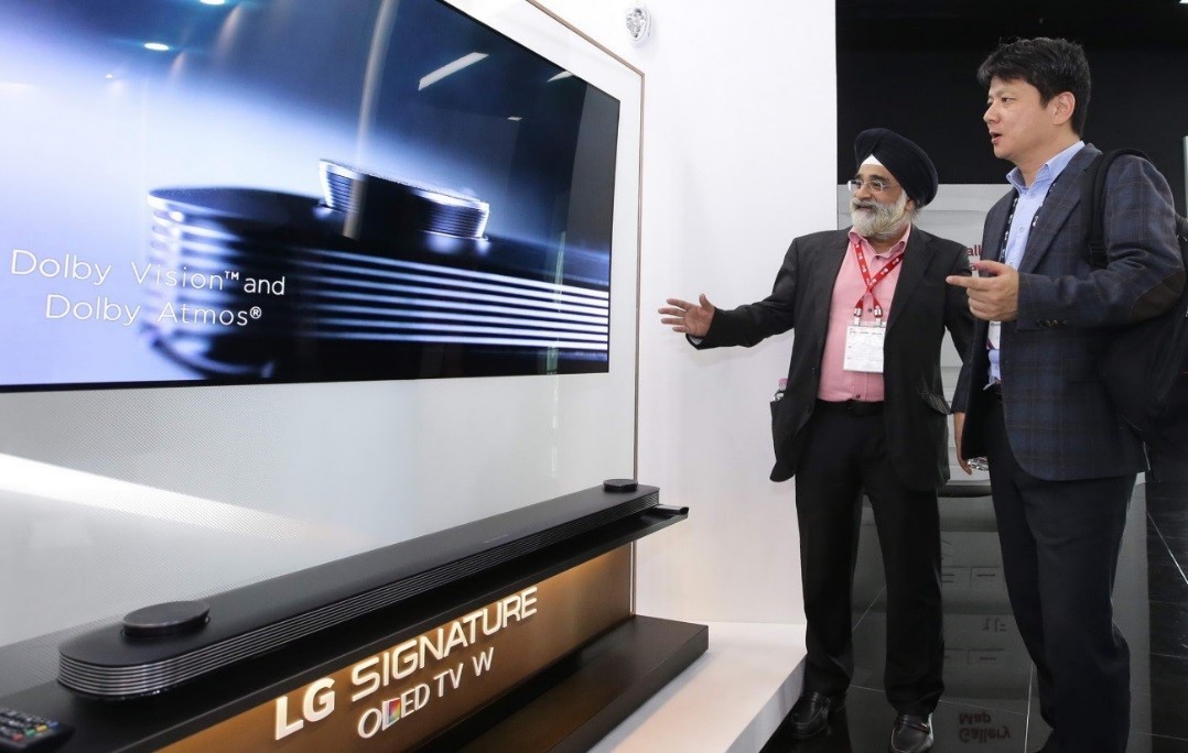 Two attendees discuss the Dolby Vision and Dolby Atmos technologies implemented in LG SIGNATURE OLED TV W.