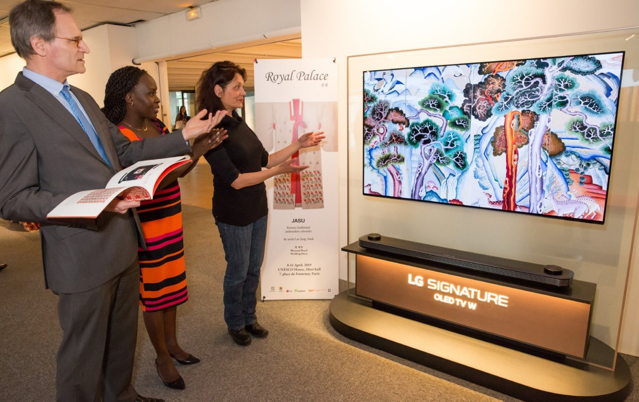Three visitors look at the LG SIGNATURE OLED TV W which displays a “chasu” artwork.