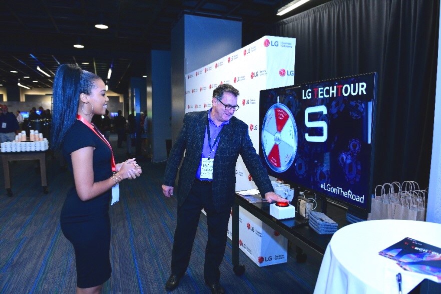 LG TechTour 02 A woman takes an attendee through LG’s promotional spin the wheel game.