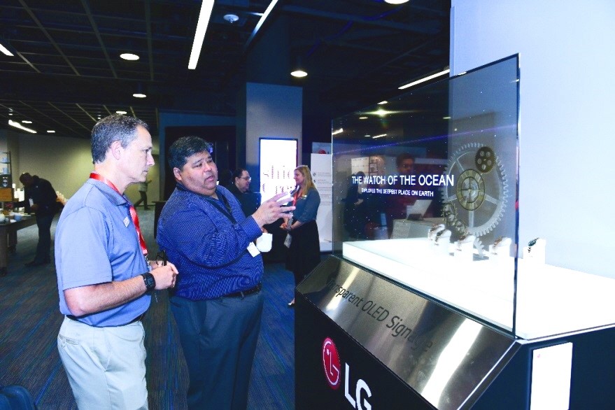 Two attendees discuss about the new Transparent LG OLED display.