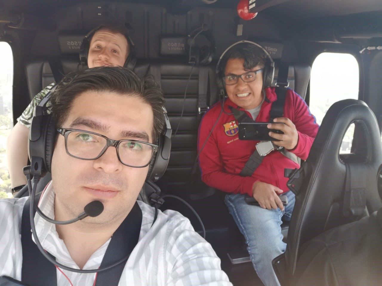 A selfie of three people in the helicopter taken by the pilot