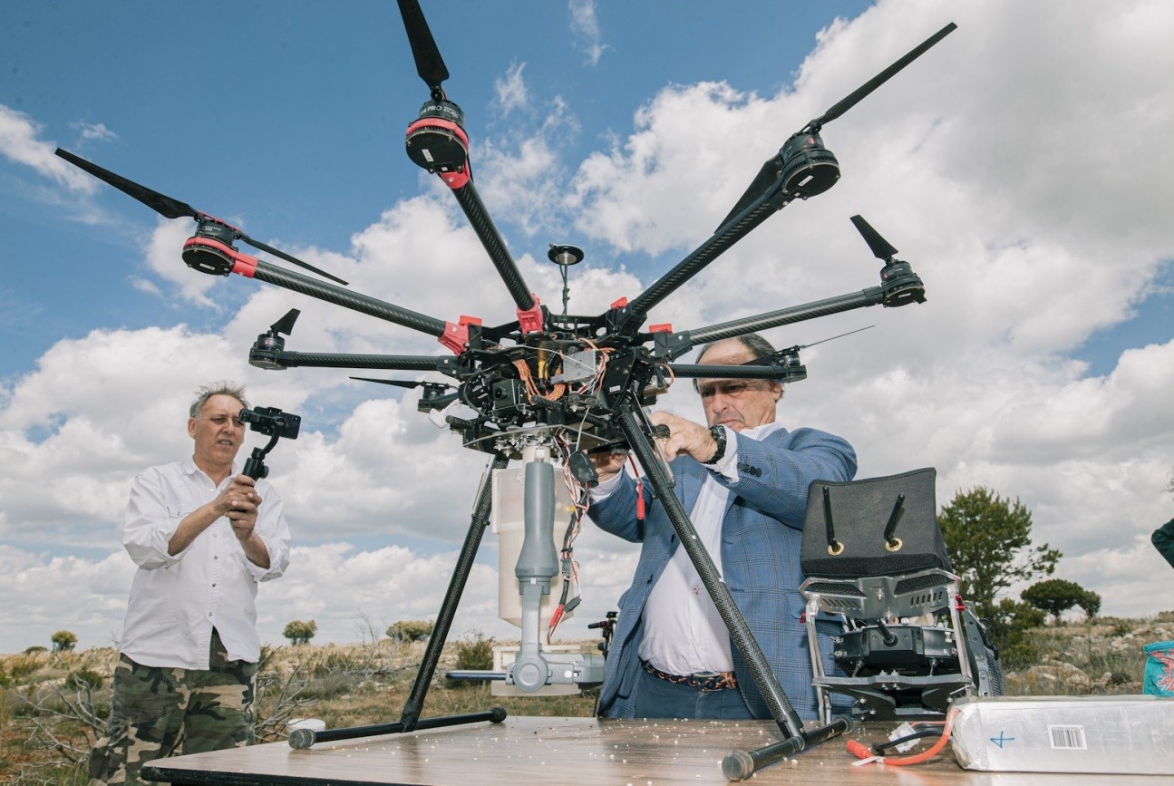 A project’s associates equip the drone with some analytic devices while another man records it with a camera.