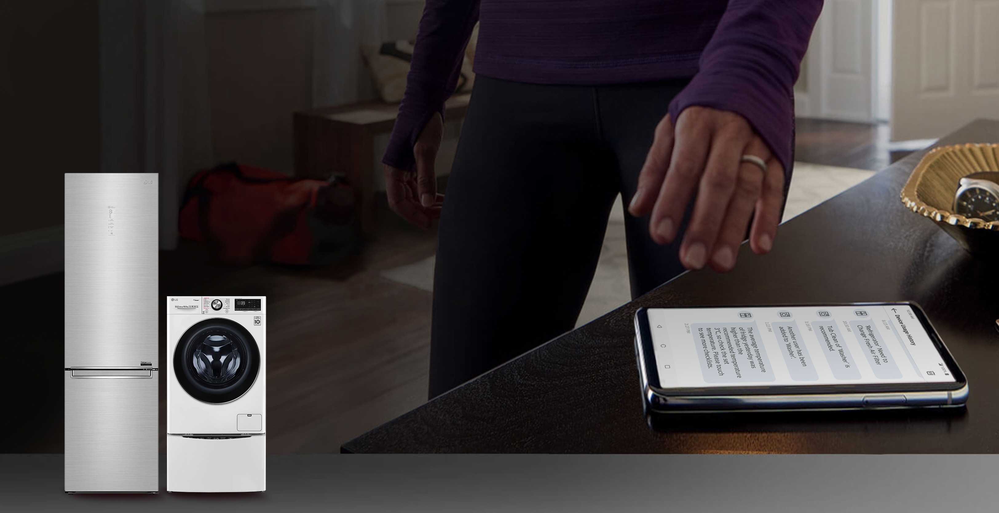 Hand reaching out to a smartphone displaying Device Usage History featuring an LG bottom-freezer refrigerator and TWINWash™ washing machine in the lower left corner