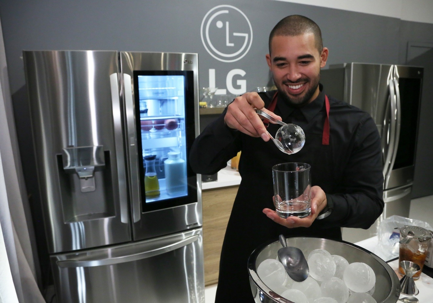 Elliot Clark, Apartment Bartender founder holds a round LG Craft Ice above a whiskey glass.