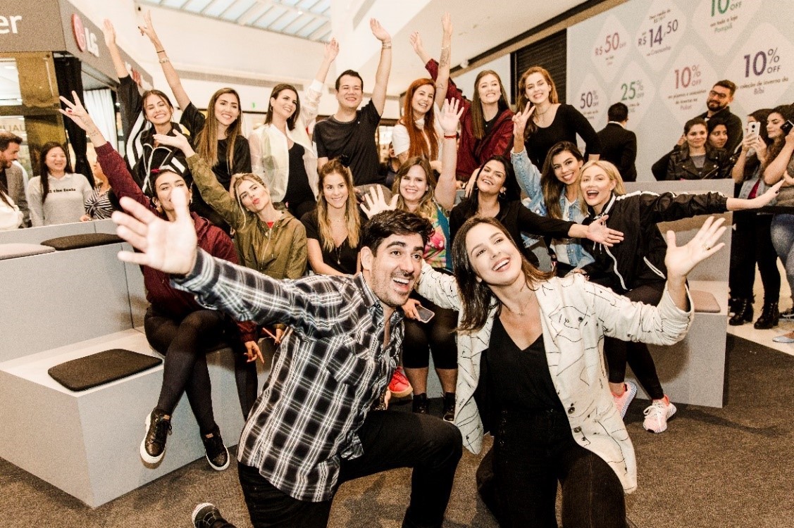 Social media celebrities take a group photo with their hands raised high.