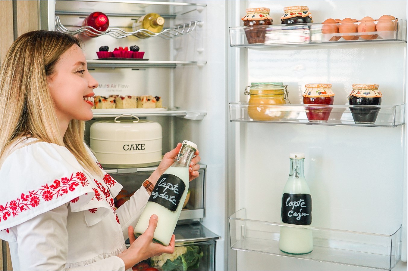 A look inside the LG refrigerator’s interior as a woman poses with a bottle of milk after taking it from one of the door’s shelves.