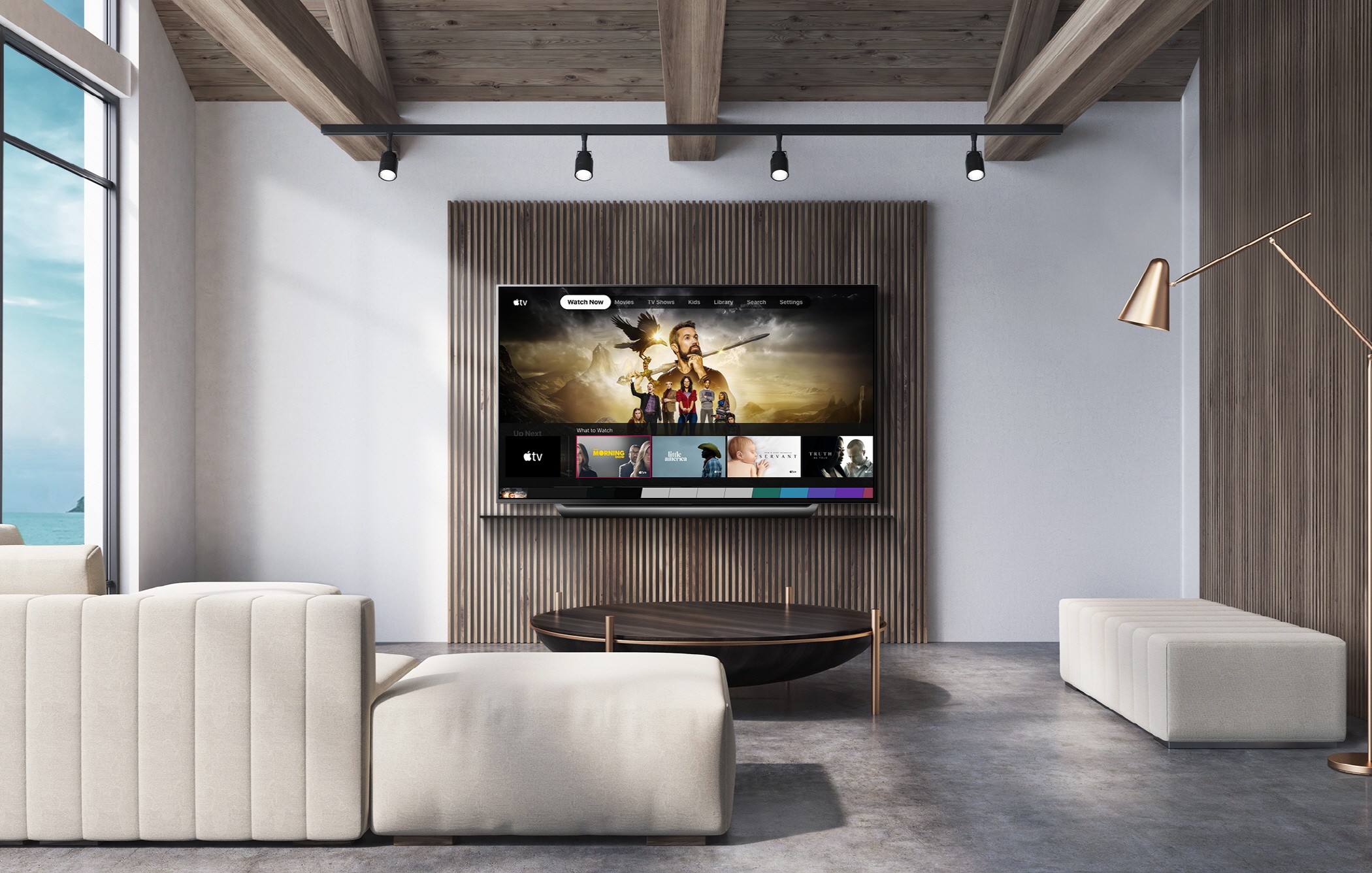 A view of an LG TV hanging on the wall of a wide modern living room as it displays the Apple TV app.