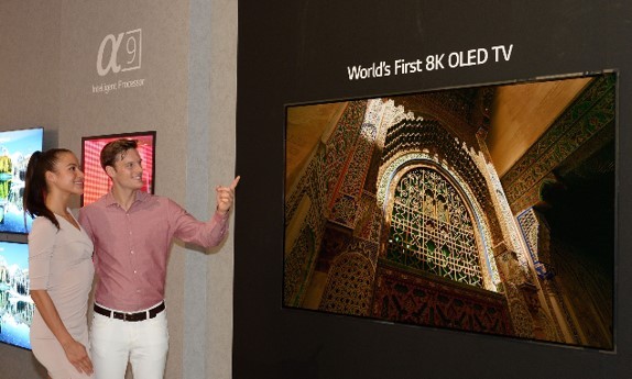 Another view of the World’s First 8K OLED TV with A9 Intelligent Processor display at IFA 2018, with a male and female model standing on the side pointing to the screen