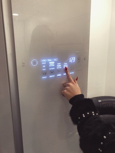 A woman pushes a button on the front door display panel of the LG Styler to set it to cleaning mode