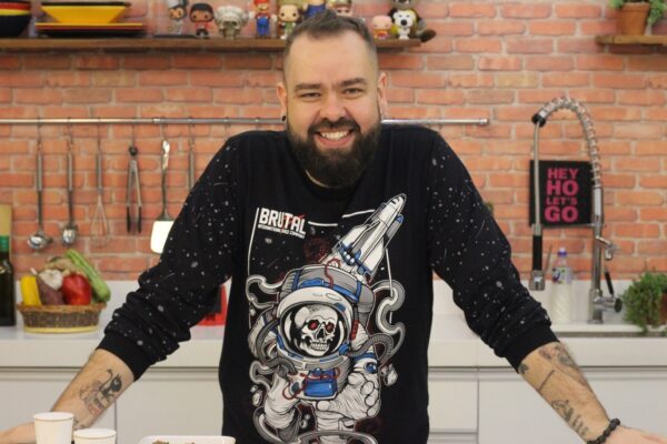 Filipe Nascimento, the star and founder of Micro Sobrevivência, smiles for the camera in his kitchen