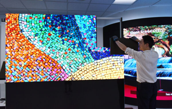 A man demonstrating how easy LG LED SIGNAGE is to install as he fits one of the final LED panels to complete a colorful display