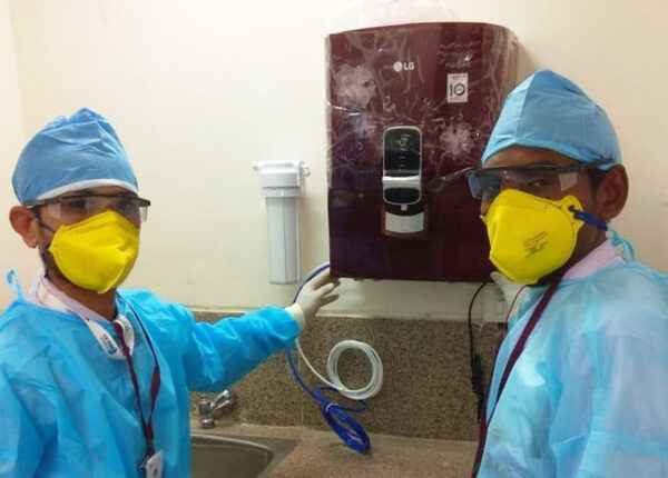 A picture of two medical workers posing in front of the LG PuriCare water purifier that has been donated to medical staff and patients