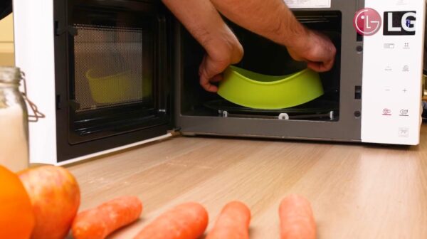 Chef Marques putting food in a green microwavable dish into LG NeoChef