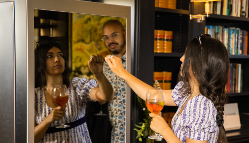 Two attendees to the LG SIGNATURE Goodwood races event check out the LG SIGNATURE Wine Cellar while testing its InstaView feature by knocking on its glass panel