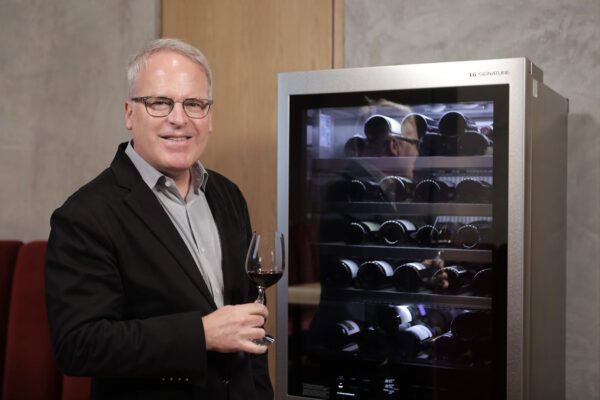 Wine critic and global brand ambassador James Suckling poses next to LG SIGNATURE wine cellar with a glass