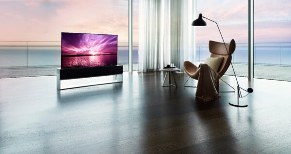 LG SIGNATURE OLED R inside a bright modern space with expansive windows in Full View Mode, a its true-to-life color displays a purple sunset that harmonizes with the coastal view outside