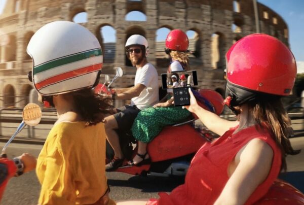 Four friends ride scooters in front of the Colosseum while a passenger uses LG WING’s unique camera capabilities to capture the action perfectly