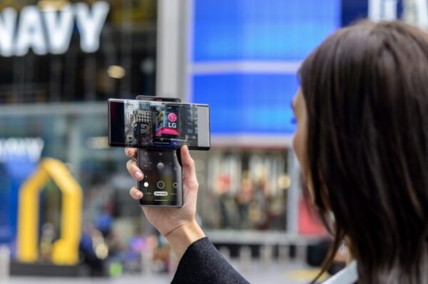 A woman taking a picture of the LG advertisement screen displayed in Times Square with LG WING in Swivel Mode