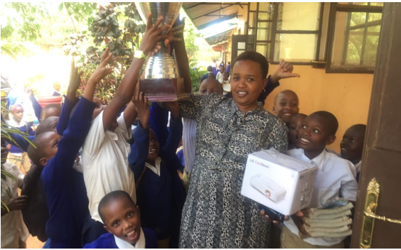 A teacher and students of a Tanzanian elementary school holding up FC Cambounet's trophy and the LG CineBeam projector donated to them to provide a better educational environment.