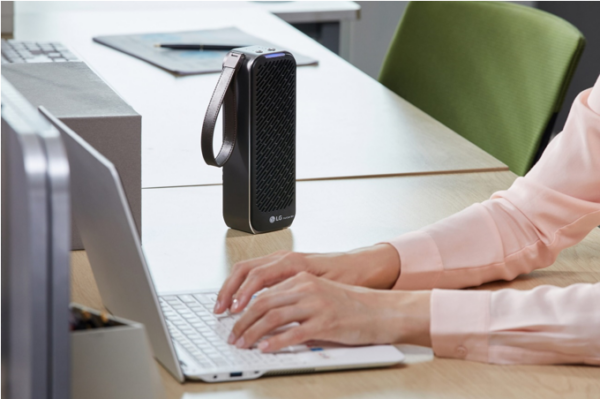 A person working on their laptop uses PuriCare™ Mini Air Purifier on the desk to keep the working environment pleasant.