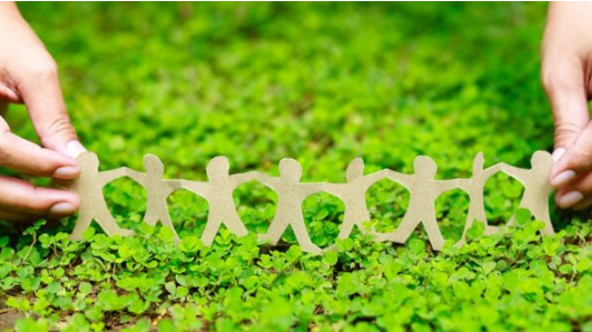 A person holding a paper chain family on a bed of grass. 