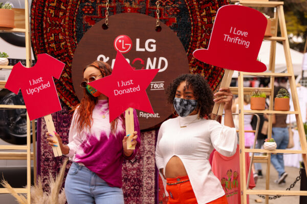  Two people holding up signs to help promote The Second Life Campaign and encourage more people to donate and upcycle their clothing