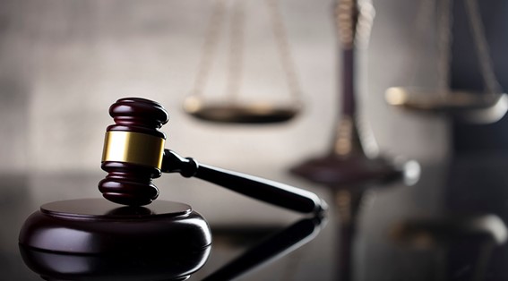 A photo of a gavel with the scales of justice in the background