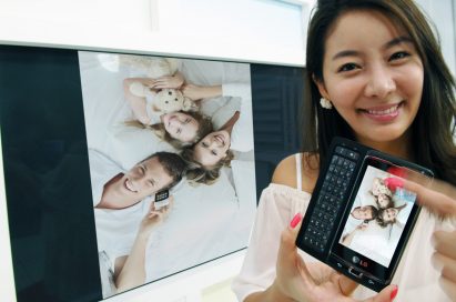 A female model is showing a family photograph on the TV by using LG’s unique multimedia sharing technology on her LG Optimus 7