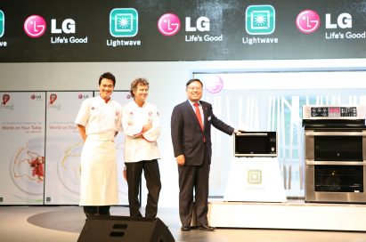 Two chefs and one LG executive pose at the front of the stage with the LG microwave and cooking oven