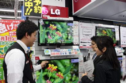 A man explains LG’s LED LCD TVs to two visitors at an LG store booth set up in Japan