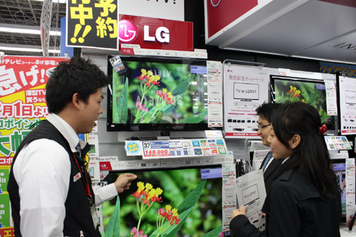 A man explains LG’s LED LCD TVs to two visitors at an LG store booth set up in Japan