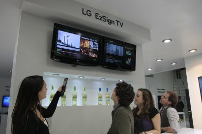 A woman demonstrating the LG EzSign TV to three visitors at ISE 2011