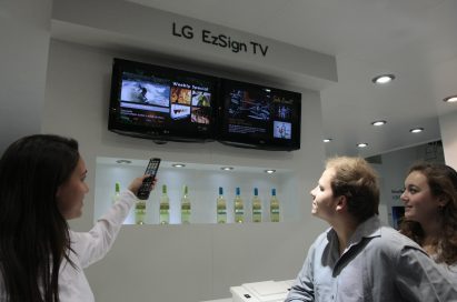 A woman demonstrating the LG EzSign TV to two visitors at ISE 2011