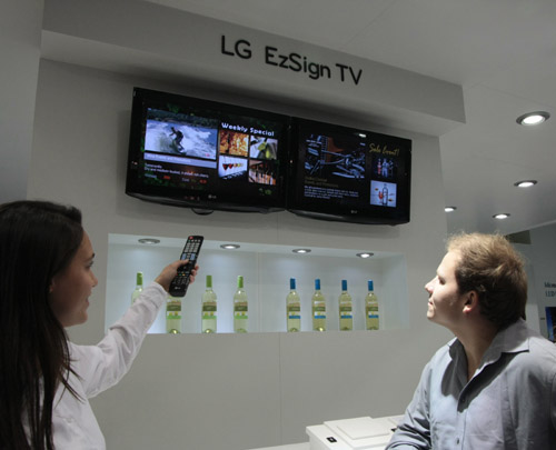 A woman demonstrating the LG EzSign TV to two visitors at ISE 2011.