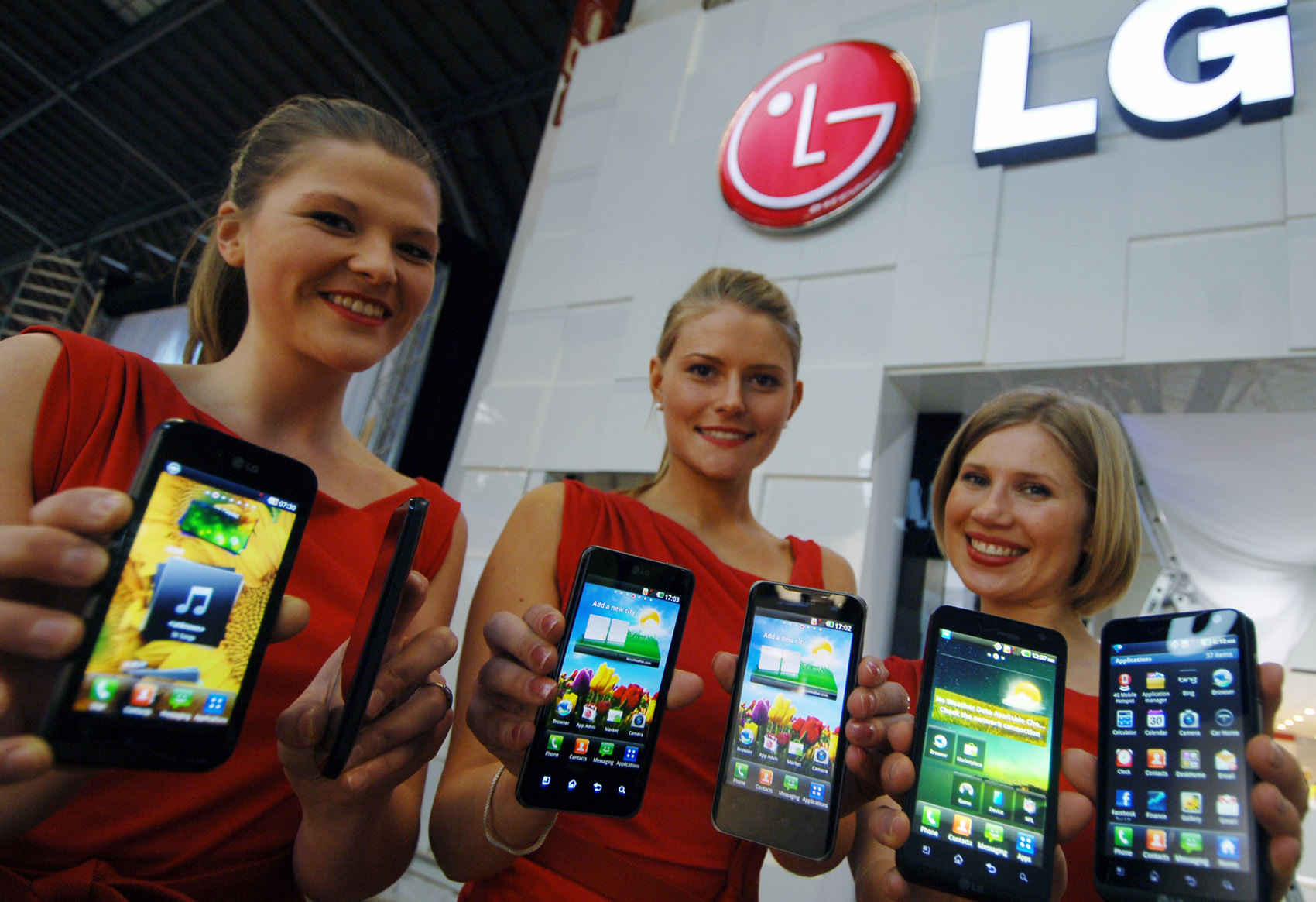 Three female models hold LG Optimus 3D, LG Optimus 2X and LG Optimus Black and show its front views at LG Booth in MWC 2011 event venue