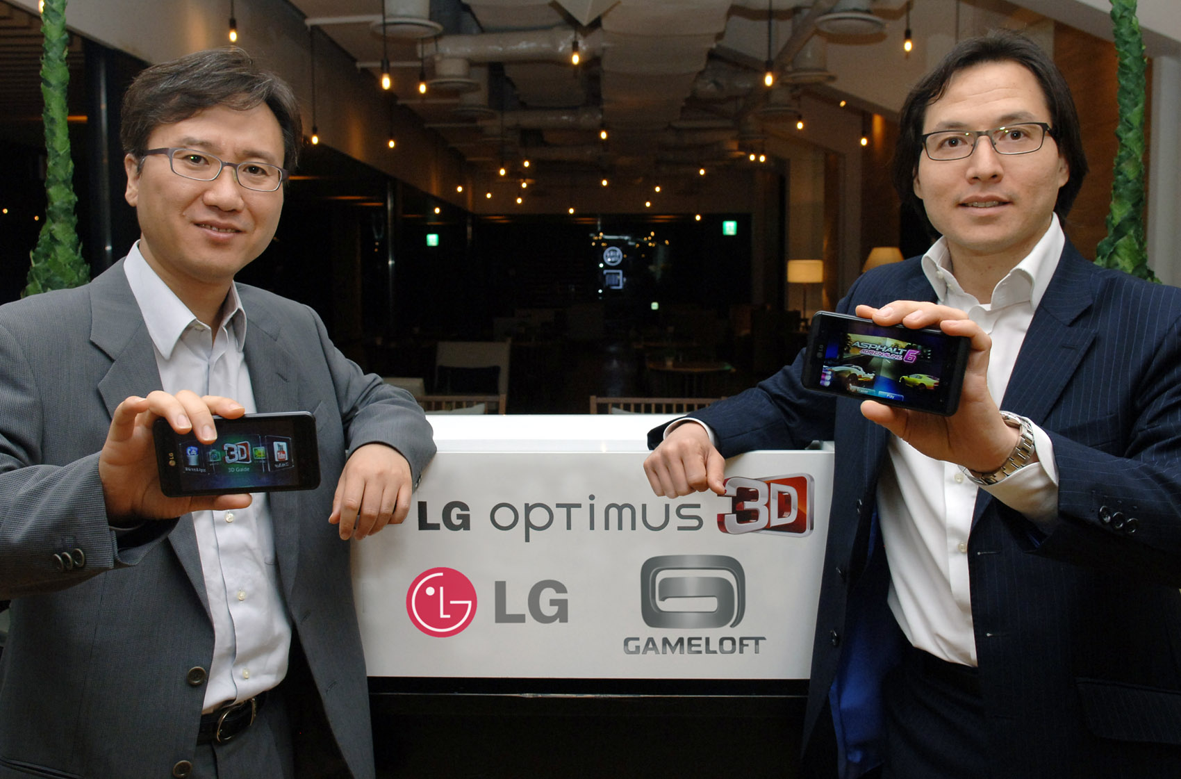 Yong-seok Jang, vice president of Business Strategy at LG Electronics Mobile Communications Company, and a representative of Gameloft hold LG Optimus 3Ds, showing the devices front