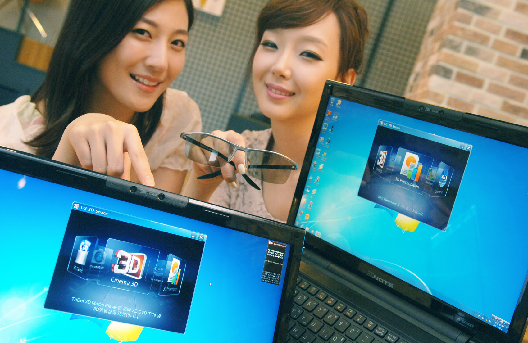 Two models present LG 3D notebooks while one of them holds 3D glasses